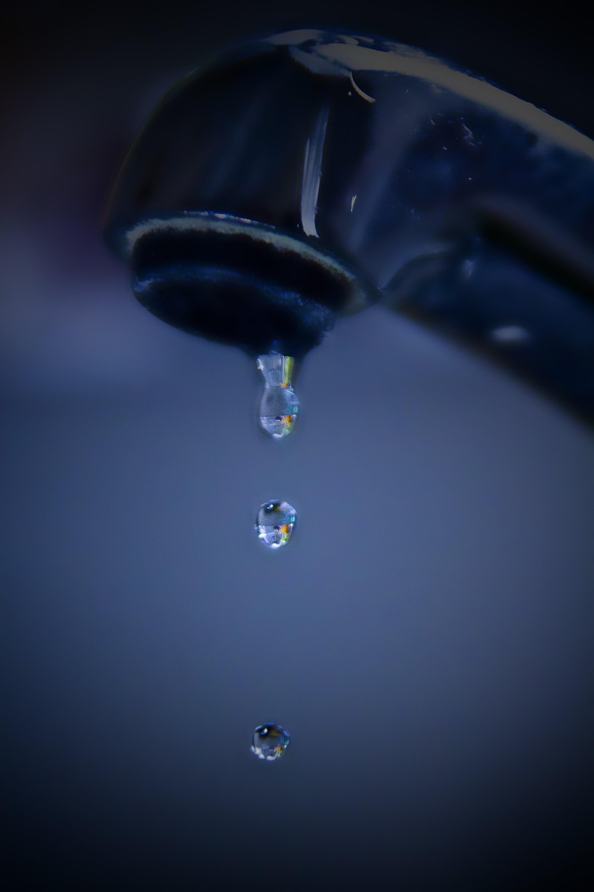 Close-up of a faucet with slow-dripping water, highlighting potential backflow problems.