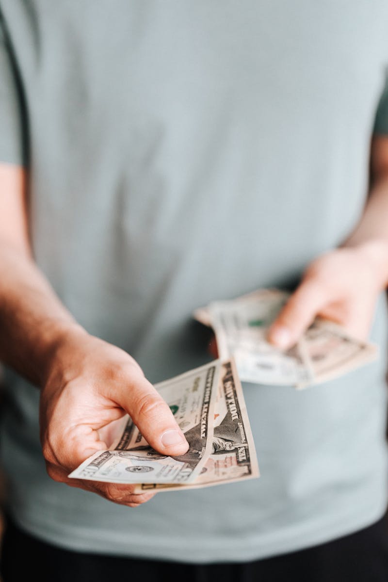 Person handing cash for plumbing services, emphasizing backflow maintenance costs.
