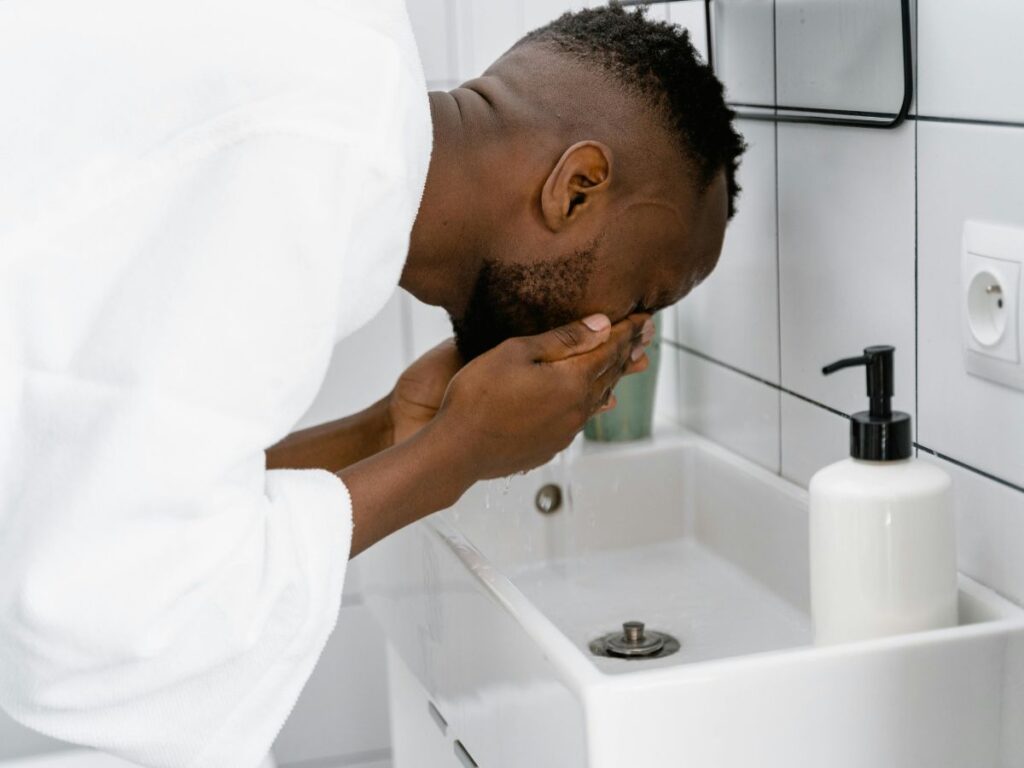 Man rinsing face – water safety affects skin and health.