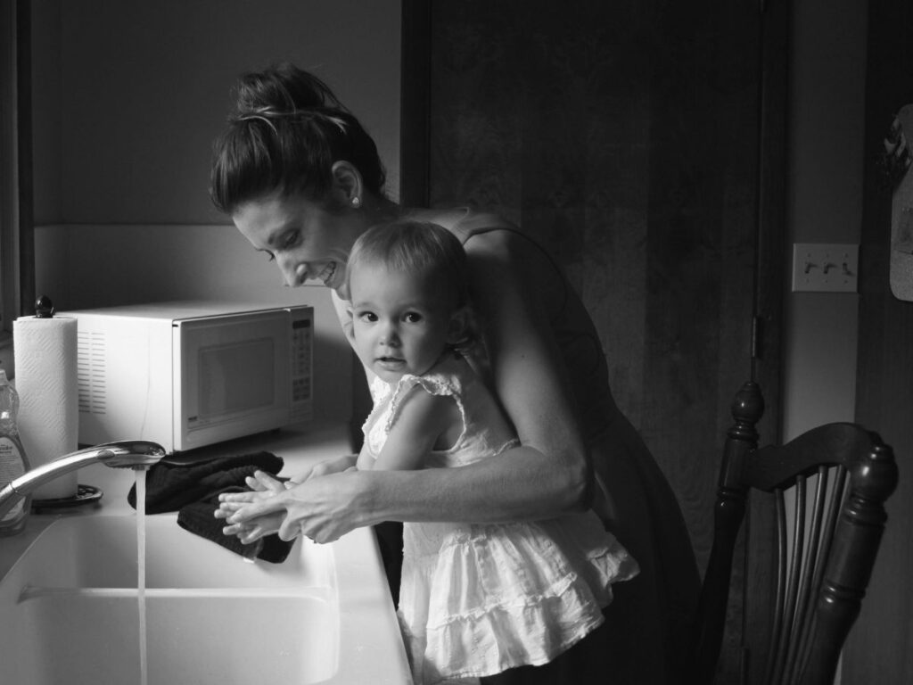 Child with mother washing hands – safe water crucial for family health.