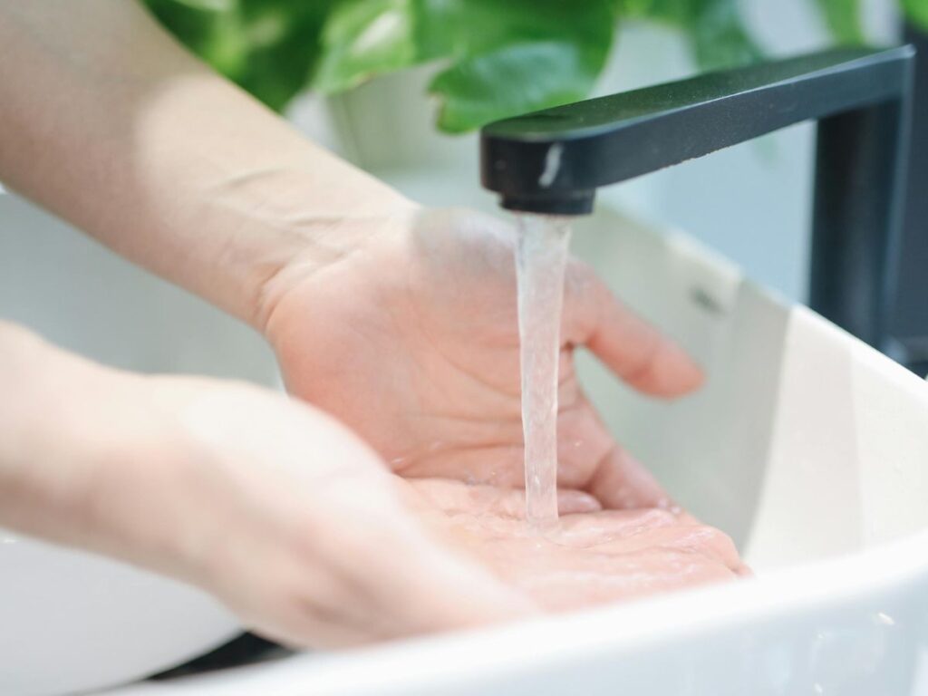 Close-up of hand under tap – clean water delivery shown in action.