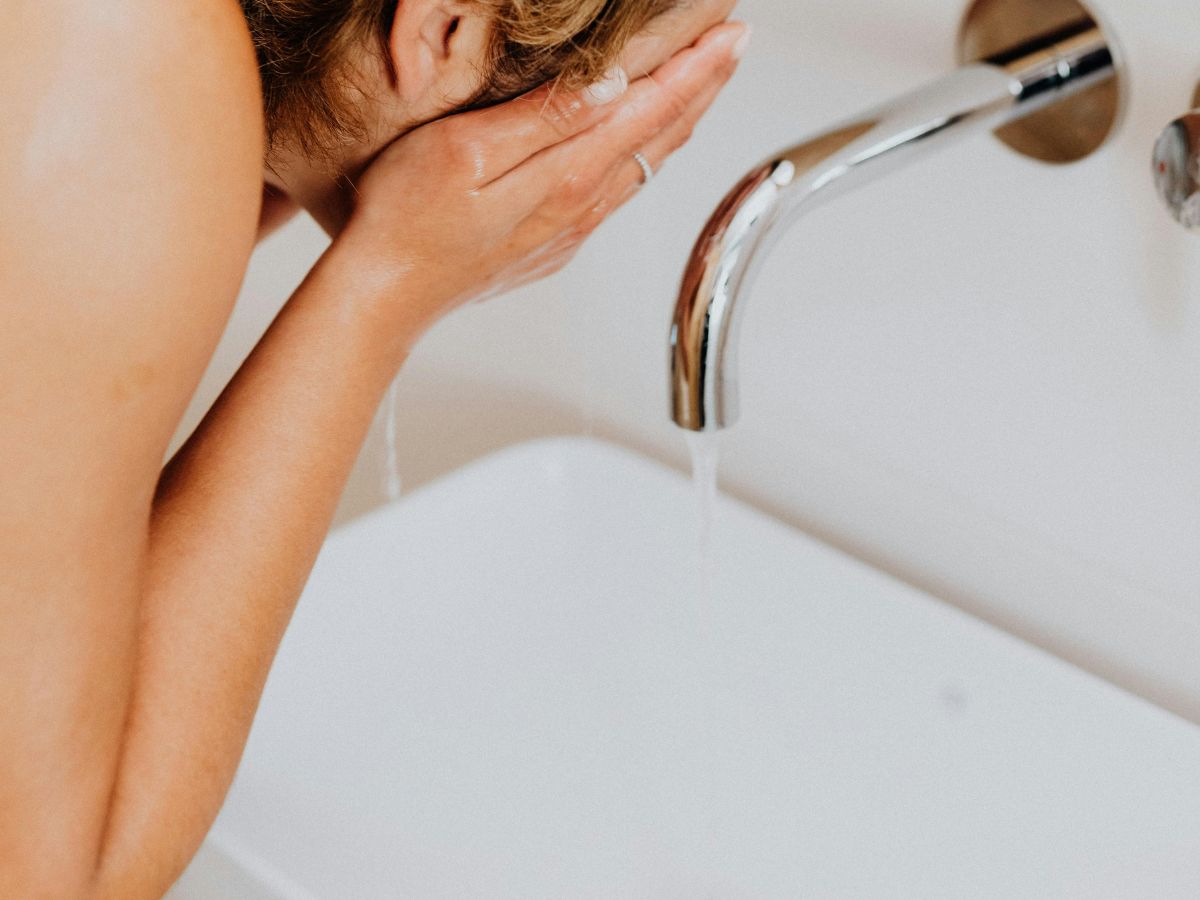 Woman splashing face with water – clean water for hygiene and health.